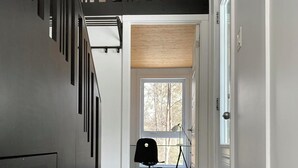 Un interior moderno con una escalera, un escritorio y una silla en un pasillo.