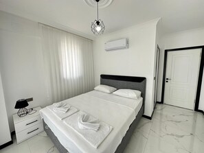 A modern hotel room with a large bed, a bedside table with a lamp, a wall-mounted air conditioner, and a door. - Star villa 1 Spacious 4-bedroom villa in adorable Dalyan with AC (Dalyan)