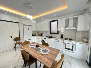 A modern kitchen with white cabinetry, a wooden dining table, and a built-in oven. - Star villa 1 Spacious 4-bedroom villa in adorable Dalyan with AC (Dalyan)