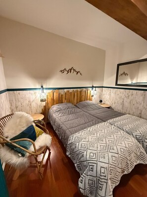 A bedroom with a bed, a chair, a nightstand, and wall-mounted lights. - Apartment in La Molina (Alp)