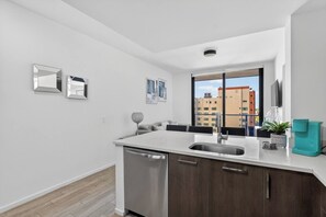 Una cocina moderna con lavavajillas, un fregadero y una ventana con vistas a edificios.