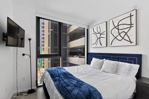 Een moderne slaapkamer met een groot bed, een televisie en kunst aan de muur.