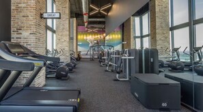 Un gimnasio con cintas de correr, máquinas de pesas y un mural en la pared.
