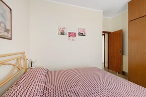 A bedroom with a bed, a wooden headboard, a wall-mounted light, and a door. - Apartment with Sea and Nature Views (Colle d'Orano)