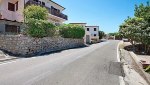 Una calle estrecha flanqueada por muros de piedra y edificios con balcones.