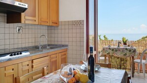 Una cocina con armarios de madera, una campana extractora de acero inoxidable y vistas al mar a través de un ventanal grande.