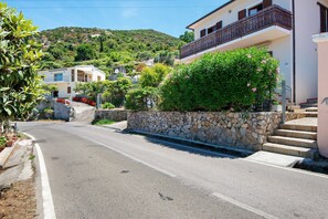 A residential street with houses, a stone wall, and a hillside in the background. - Apartment with Sea and Nature Views (Colle d'Orano)