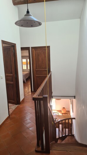 Un escalier avec des rampes en bois et un luminaire suspendu.