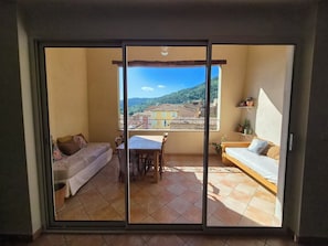 Une chambre avec un balcon, un lit, une table et un canapé.