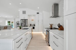 Een moderne keuken met witte kasten, een groot eiland en een inbouwoven.