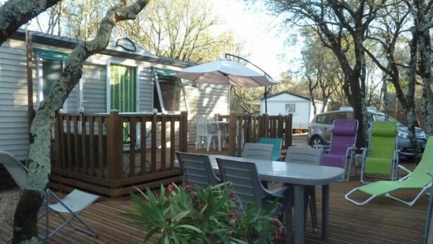 A wooden deck with a table and chairs, a small deck area, and a covered seating area. - Rent a 4/6-person mobile home at the Orgac l'Aven Municipal Campground (2 Grottes Import) (Orgnac-l'Aven)