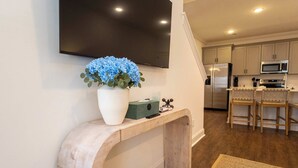 Una cocina moderna con microondas integrado, refrigerador de acero inoxidable y taburetes de madera.