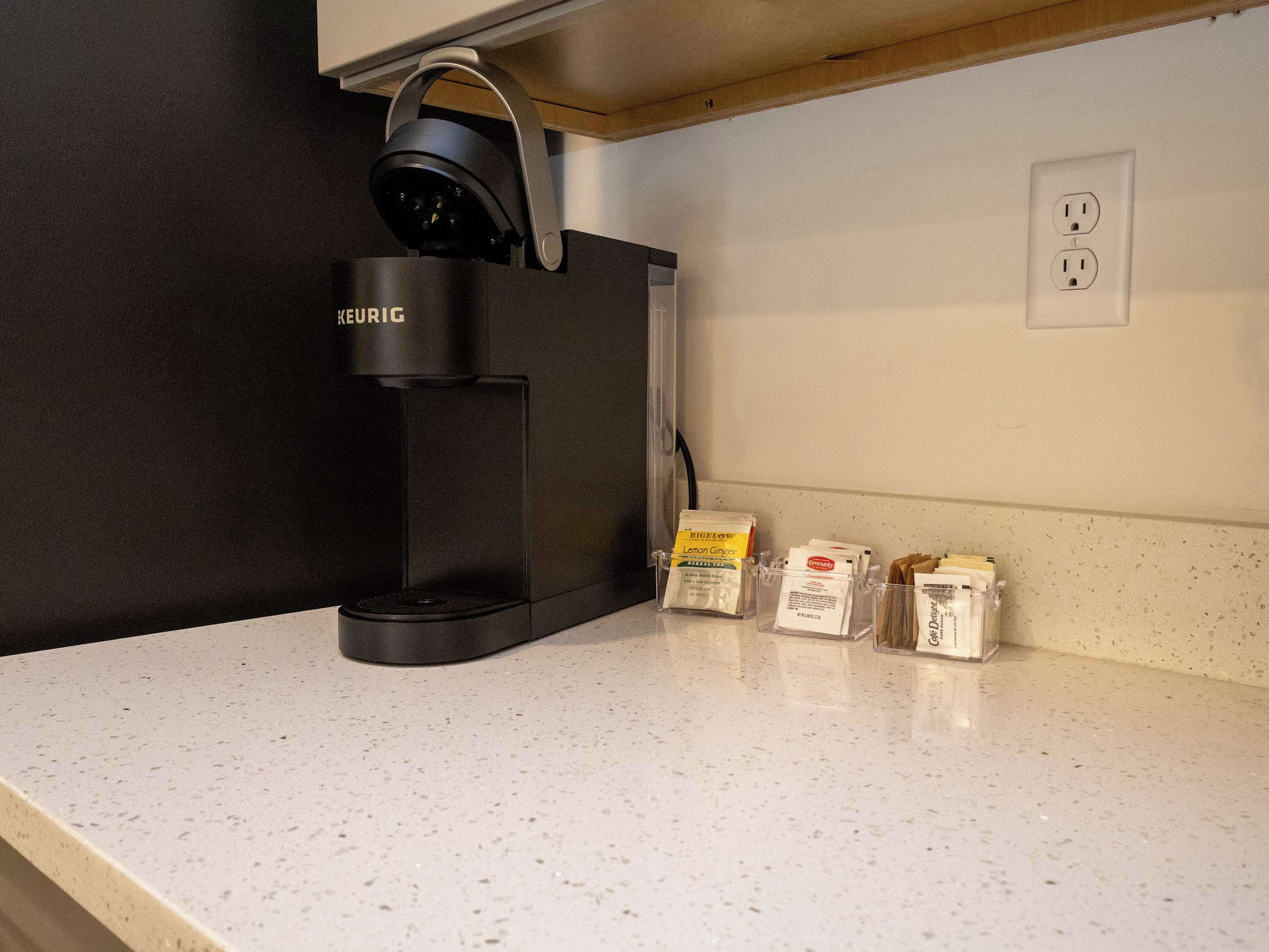 Uma cafeteira Keurig numa bancada, com um suporte para cápsulas de café contendo algumas cápsulas.