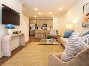 Een moderne woonkamer met een bank, een salontafel en een aan de muur bevestigde televisie.