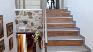 A staircase with a stone accent wall, metal railings, and wooden steps.