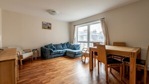 Um quarto com uma mesa de jantar de madeira, um sofá azul e uma janela com cortinas.
