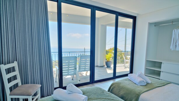 Ein Hotelzimmer mit Balkon, zwei Betten, einem Sessel und einem Kleiderschrank.