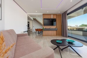 A modern living room with a sofa, a TV, a dining area, and a staircase. - Villa Niksun (Bibinje)