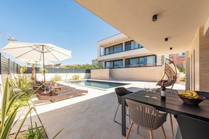 Eine moderne Außenpatio mit Pool, Liegestühlen und Essbereich mit Tisch und Stühlen.