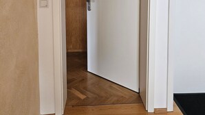 A hallway with a wooden floor leading to a white door with a silver handle.