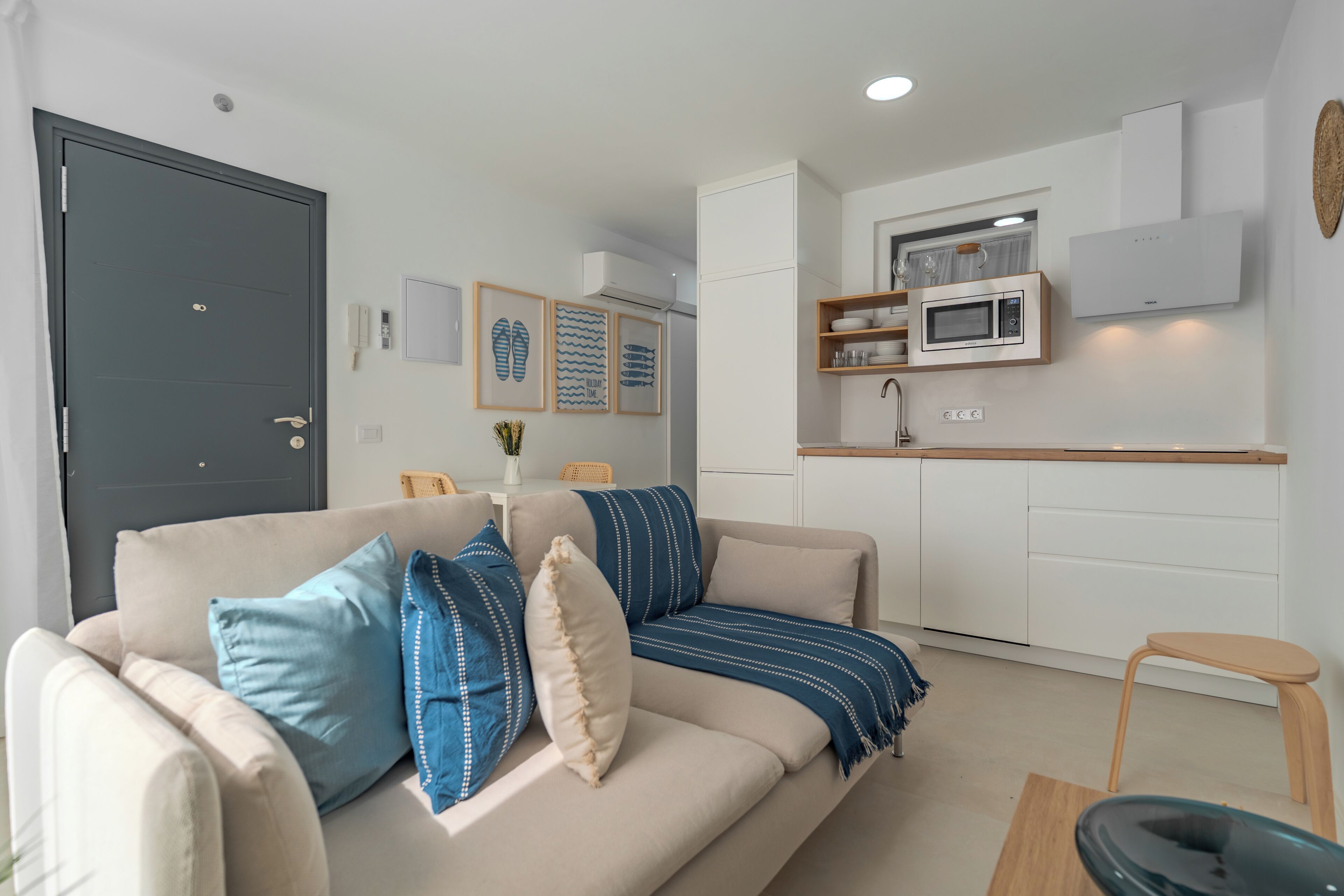 A modern living room with a sofa, a dining table, and a kitchen area with a microwave and cabinets.