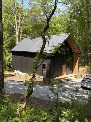 Eine Hütte mit geneigtem Dach, einer Holztür und einem Schotterweg.