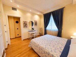 Ein Schlafzimmer mit einem Bett, einem Schreibtisch, einem Stuhl, einem Spiegel und einem Fenster mit Vorhängen.