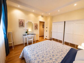 Een slaapkamer met een bed, een bureau, een stoel, een kast en een spiegel.