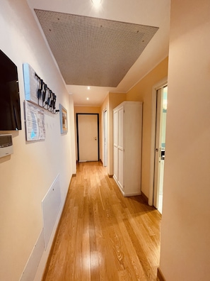 Ein Flur mit Holzboden, einem Deckenventilator, einer Tür und einem an der Wand befestigten Fernseher.