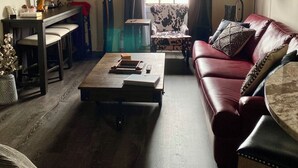 A living room with a sofa, a coffee table, a TV, a window with curtains, and a lamp. - Downtown 2 bedroom apartment. 20 minute walk to Sanford Stadium (Athens)