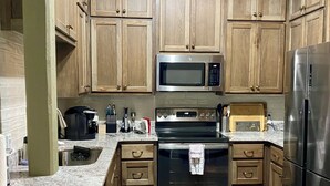 A kitchen with wooden cabinets, a stainless steel refrigerator, a microwave, an oven, and a brick floor. - Downtown 2 bedroom apartment. 20 minute walk to Sanford Stadium (Athens)