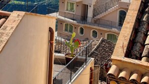 A high-rise building with balconies overlooking a coastal cityscape and a body of water. - Villa Flavio-Panoramic Boutique Rooms  (Castelmola)