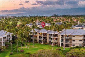 A resort with multiple-story buildings, palm trees, and a view of the ocean. - Includes Beach Gear!  E305 Vista Waikoloa (Waikoloa)