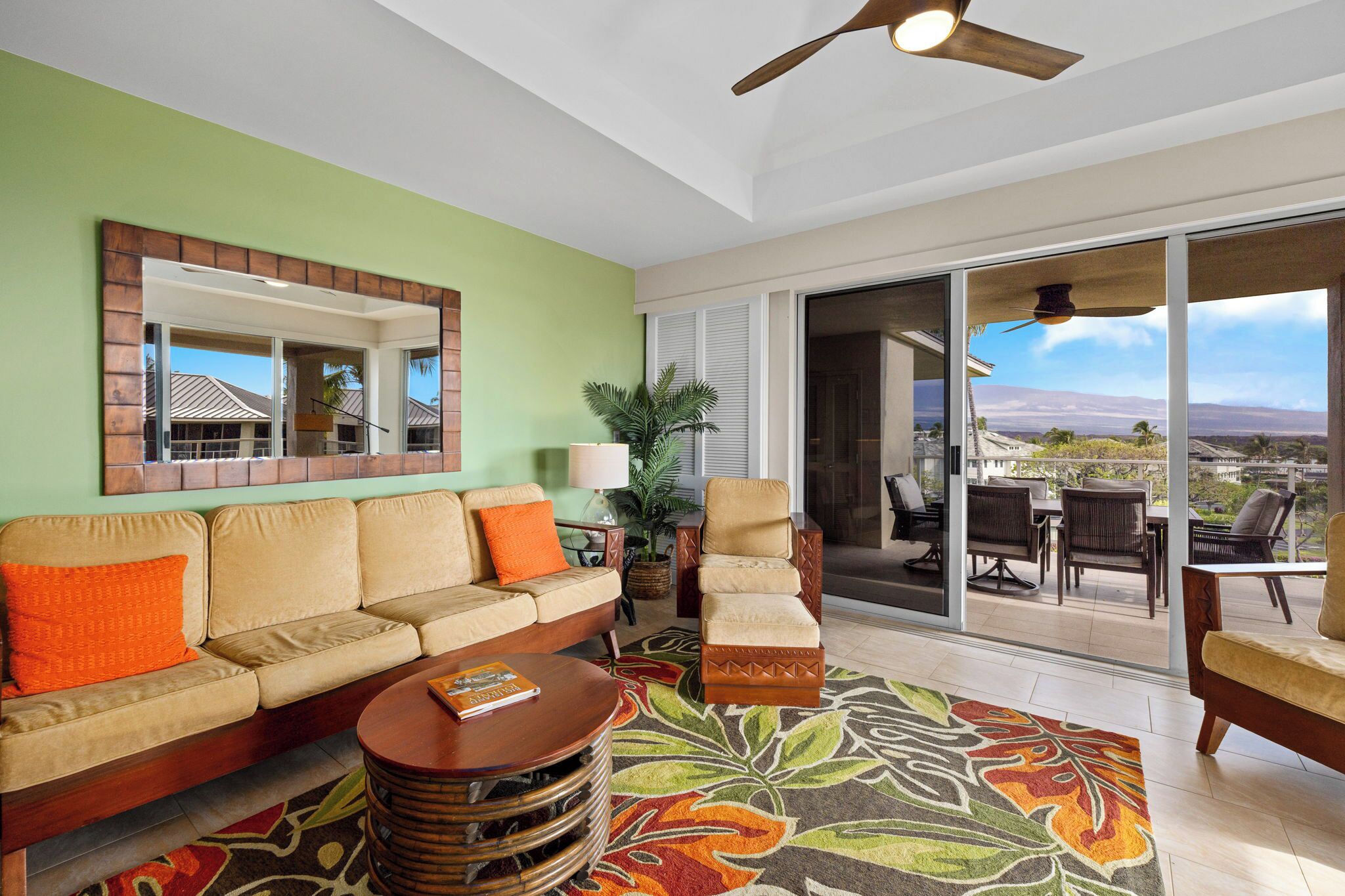 A living room with a sofa, armchairs, a coffee table, a ceiling fan, and a large sliding glass door leading to an outdoor patio.