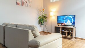 Una sala de estar con un sofá, un televisor, una planta y una lámpara.