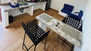 Una cucina compatta con finestra, ventilatore a soffitto e zona pranzo con due sedie.