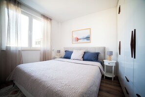 A neatly arranged bedroom with a large bed, bedside tables, a wall-mounted artwork, and a wardrobe. - Modern Family Suite in Prizren (Prizren)