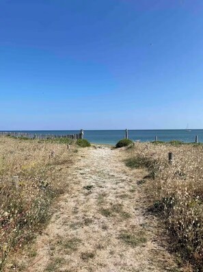 A sandy path leading to a beach with a wooden fence on one side and a sailboat in the water. - Beach House / Rhuys Peninsula (Sarzeau)