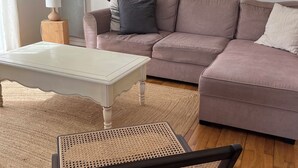 Una sala de estar con un sofá, dos ventanas redondas, una lámpara y un sillón.
