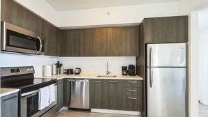 Une cuisine moderne dotée d’appareils électroménagers en acier inoxydable, de meubles en bois et d’un plan de travail de couleur claire.
