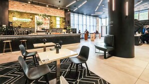 Un café moderne doté d’un bar, de coins salon et d’une grande colonne.