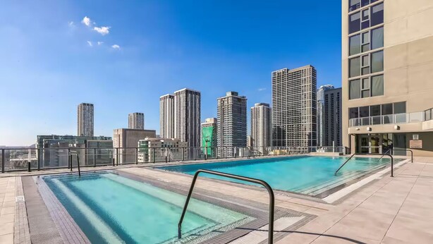 Une piscine sur le toit, avec une eau d’un bleu cristallin, entourée de gratte-ciel.