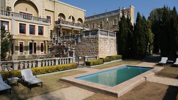 Un hotel con piscina, zona de estar al aire libre y un jardín cuidado.