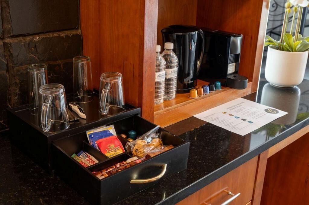 Uma área de recepção de hotel com estação de café, garrafas de água e um menu.