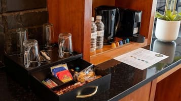 Uma área de recepção de hotel com estação de café, garrafas de água e um menu.