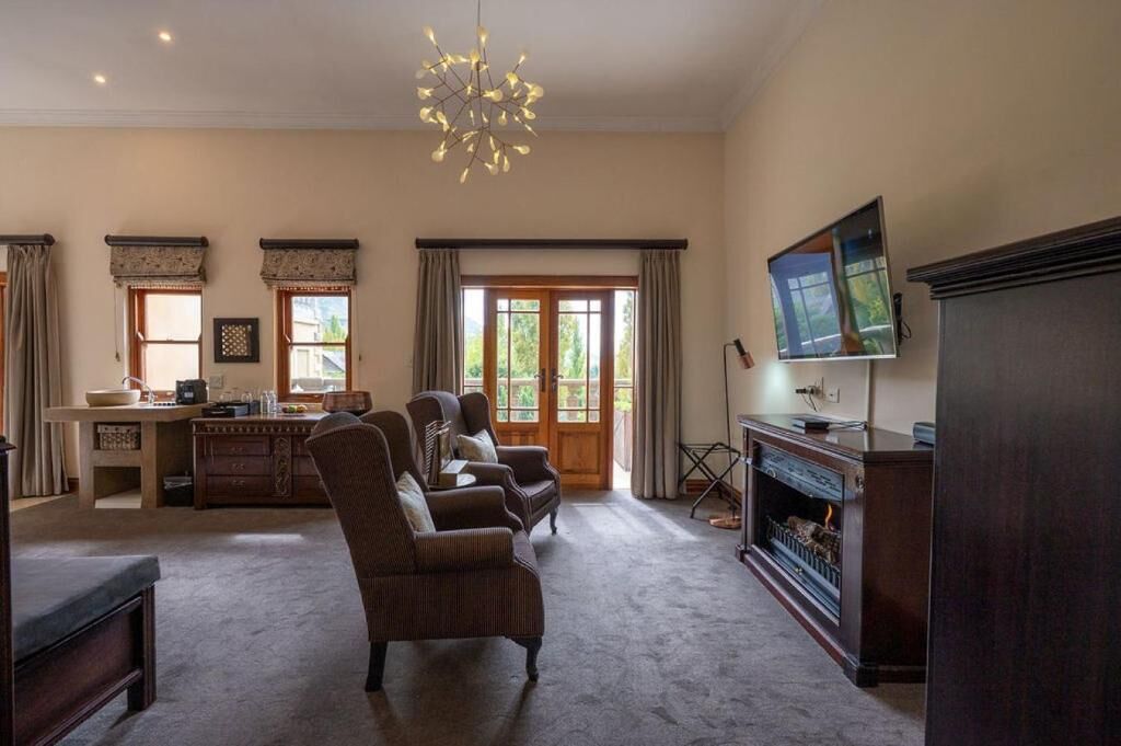 Amplia sala de estar con chimenea, televisor y comedor con mostrador de cocina.