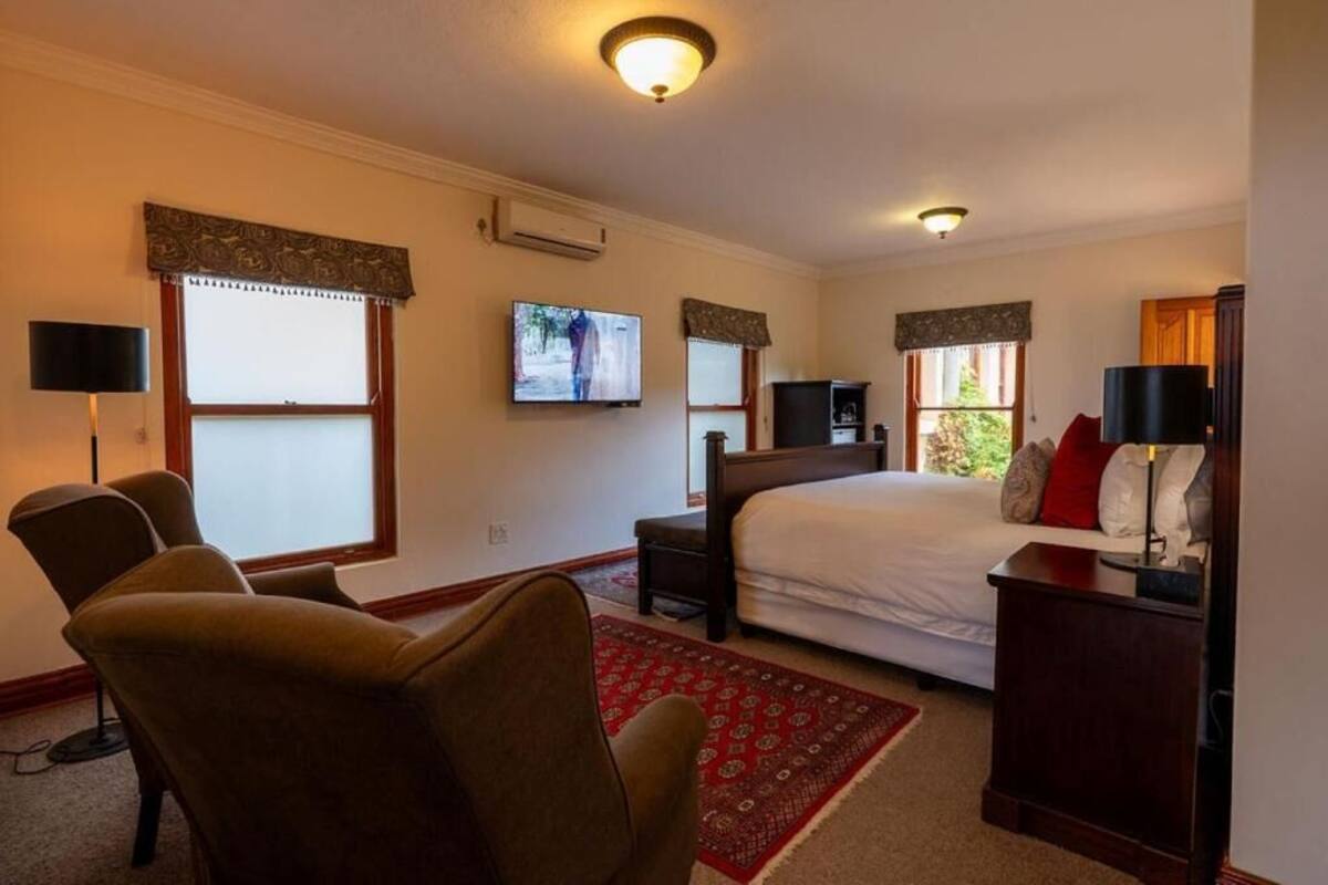 A bedroom with a bed, a TV, a desk, and a chair.