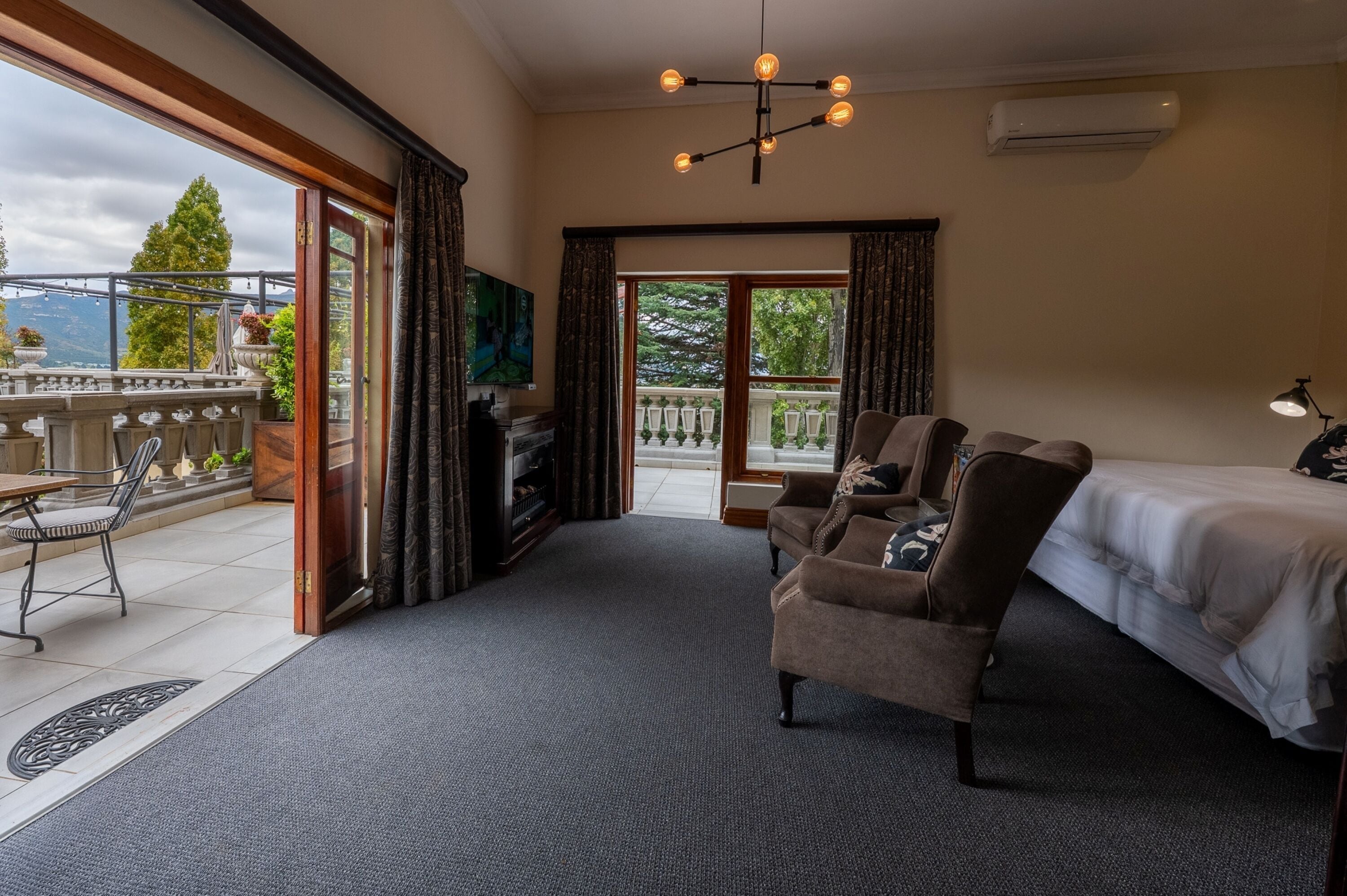 Habitación de hotel con cama, sofá, televisión y balcón con vistas.