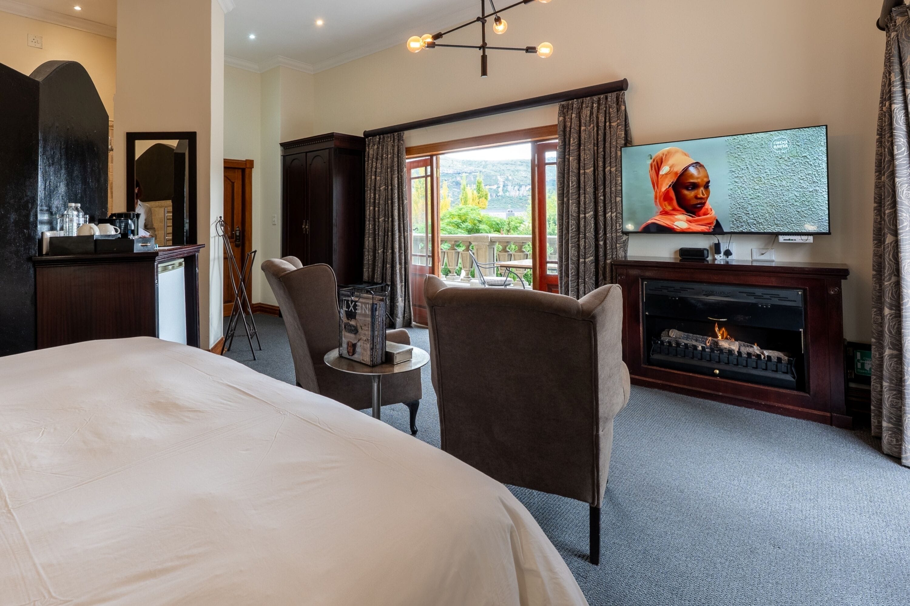 Une chambre d’hôtel équipée d’un lit, d’une télévision, d’une cheminée et offrant une vue sur l’extérieur.