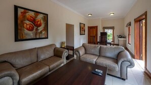 A living room with two leather sofas, a wooden coffee table, and a painting on the wall. - IL Castello Boutique Hotel (Clarens)